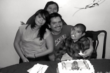 Myrna, her daugther Deloris, her husband Juan and her son Norman in front of a cream covered cake.